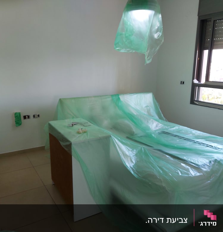 חדר עם רהיטים מכוסים בניילון לקראת צביעה